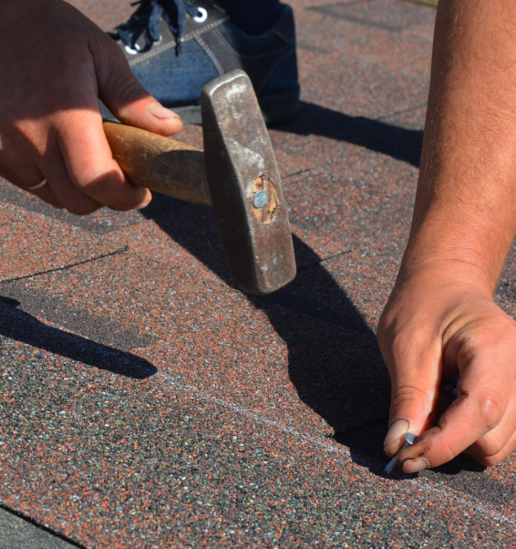 worker installing some asphalt tiles on a roofing